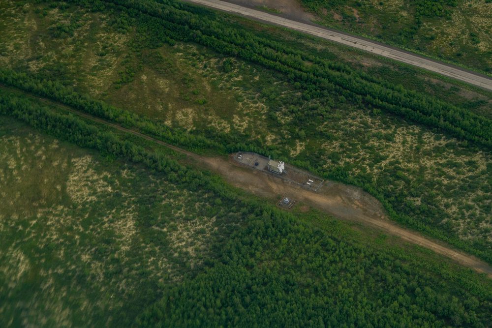 Aerial of the Dalton Highway and pipeline corridor cutting a straight line through unbroken boreal forest