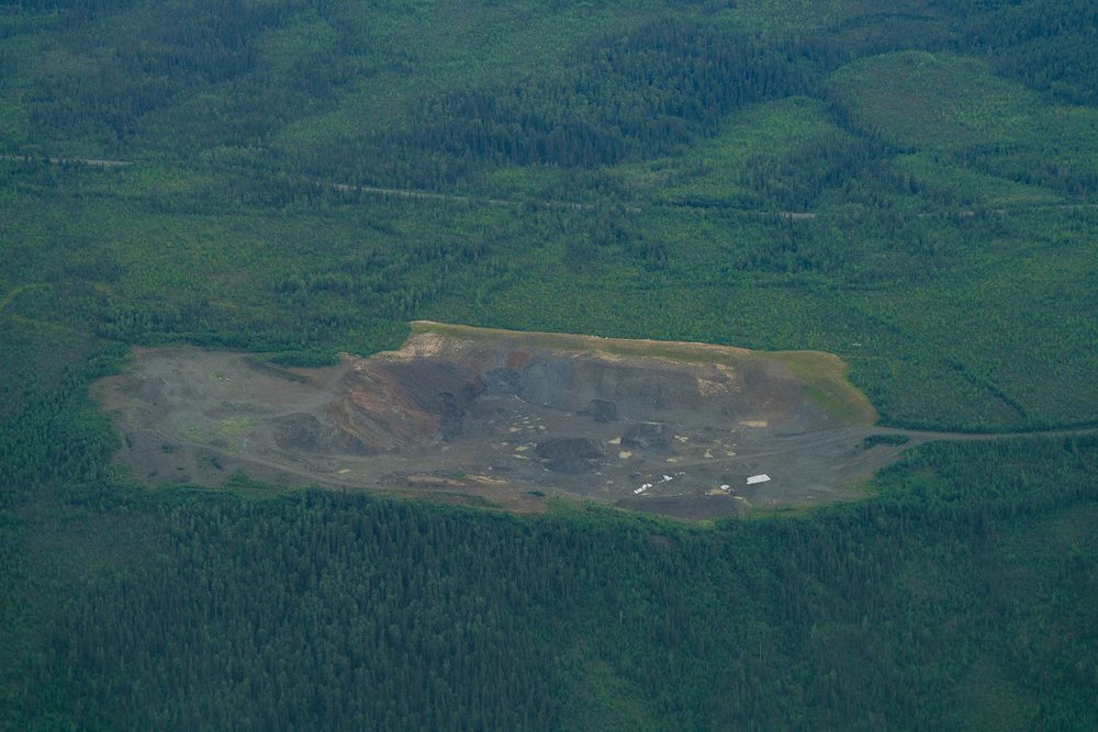 A cleared gravel pad cut into spruce forest along the Dalton corridor, from the air