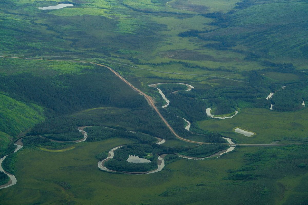 Aerial of a gravel road crossing a meandering river and its oxbow lakes