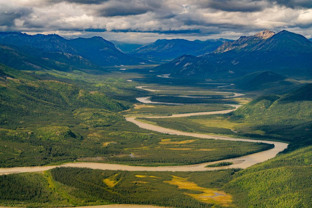 Aerial of a braided river winding through an unbroken valley in the Brooks Range, no road or structure anywhere in the frame