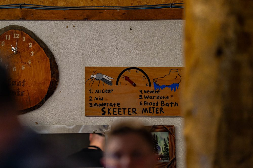 A hand-painted mosquito severity sign on a roadhouse wall reading from All Clear to Blood Bath