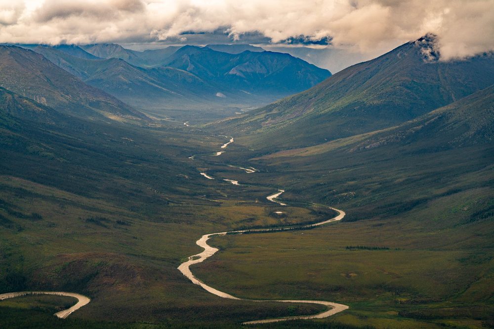 A braided river winding down an unbroken valley in the Brooks Range under low cloud