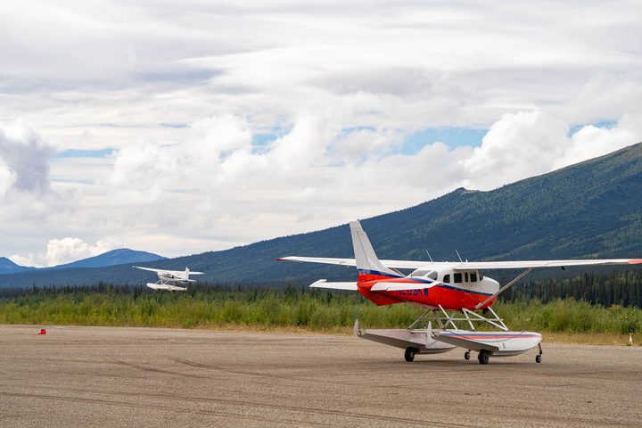 Bush planes on a gravel airstrip below the mountains