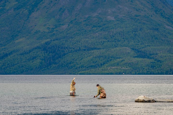 Two anglers wading a lake below the range, one mid-cast