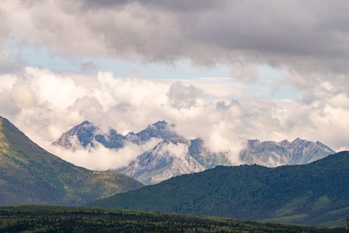 Peaks half hidden in cloud beyond a green valley
