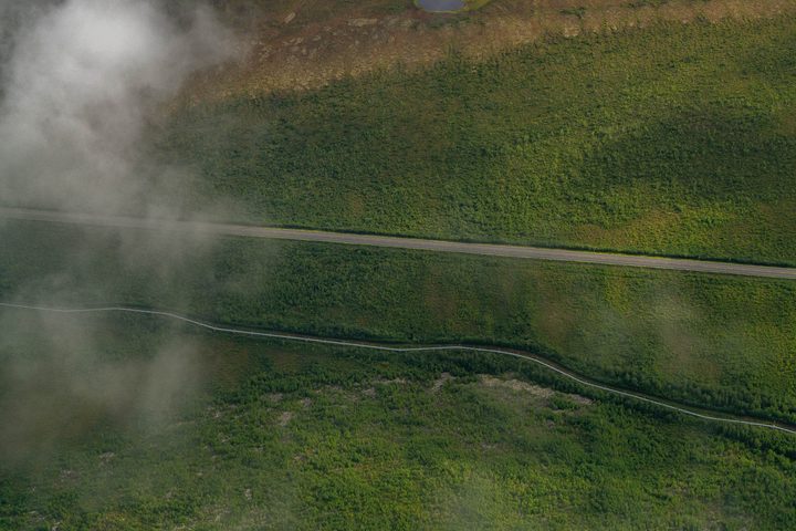 The haul road and the pipeline through forest, seen through breaking cloud