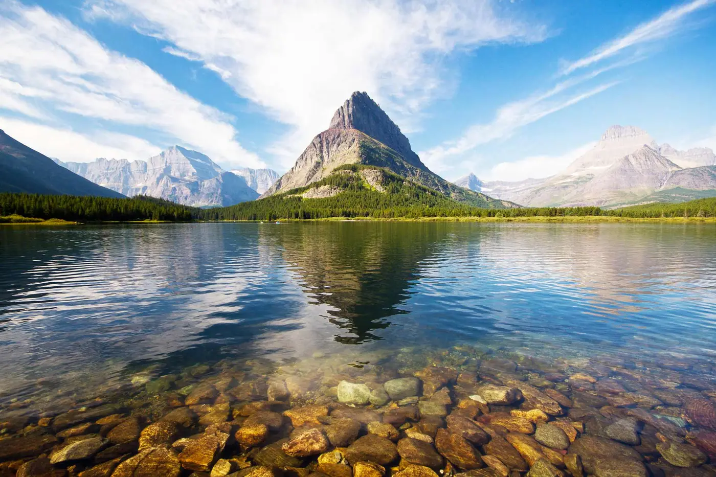 Alpenglow on the peaks above a still lake in Glacier National Park