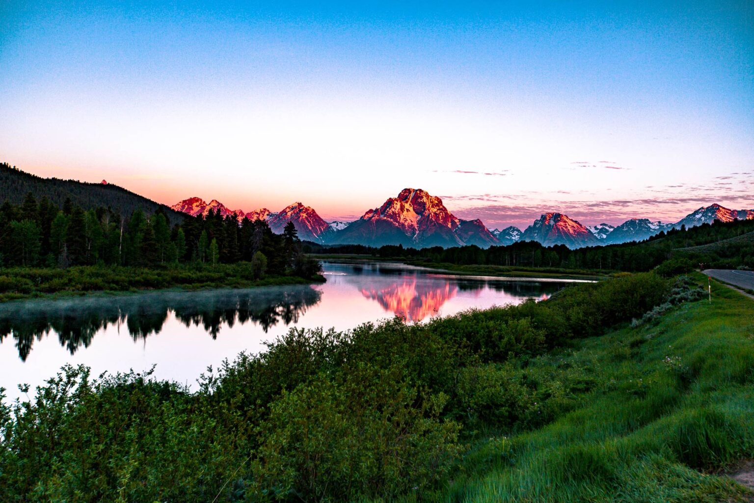 Oxbow Bend at sunrise with the Tetons lit pink.