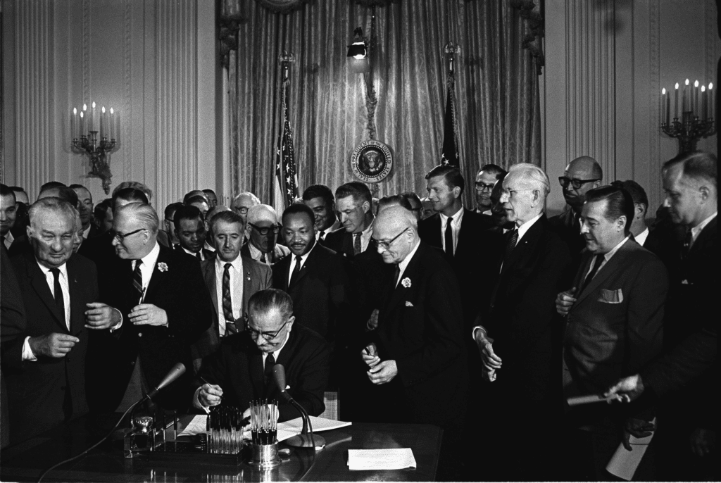 President Lyndon B. Johnson signing the historic Civil Rights Act with Dr. Martin Luther King, Jr. looking on | Best Black History & Civil Rights Sites