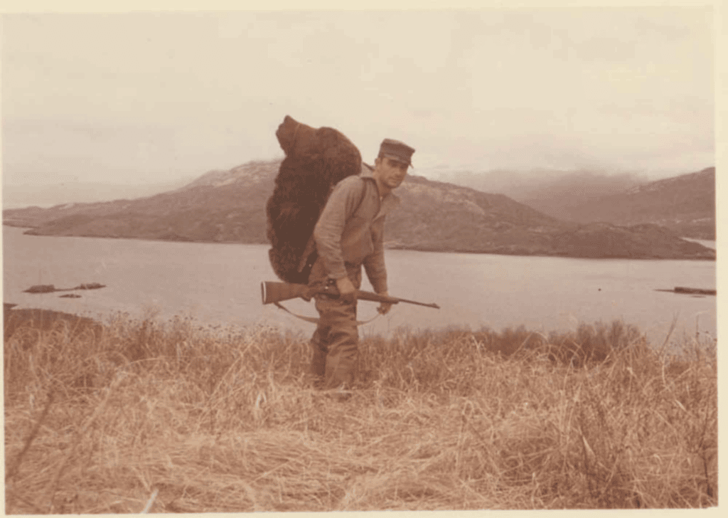 Bear hunter with huge bear head strapped to his back 