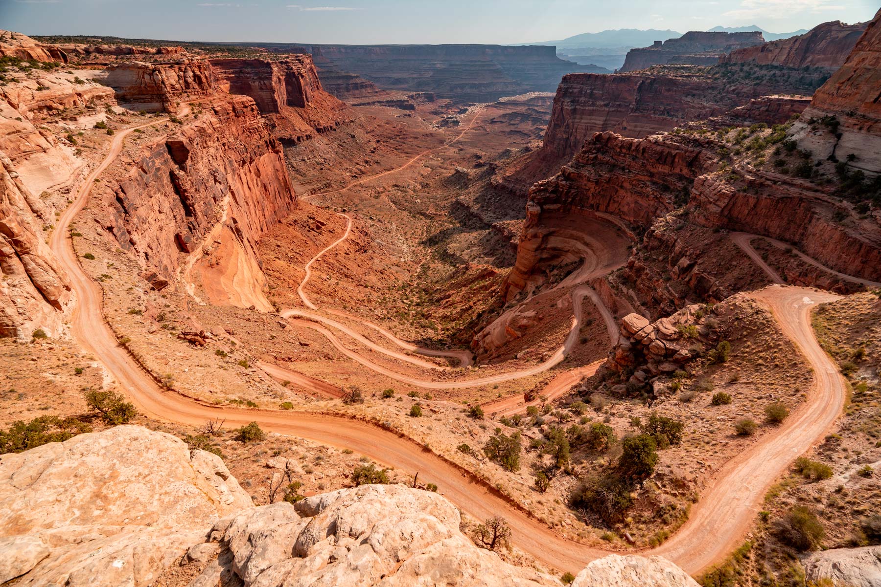 A trail weaves down a rust colored mountain in Canyonlands National Park.