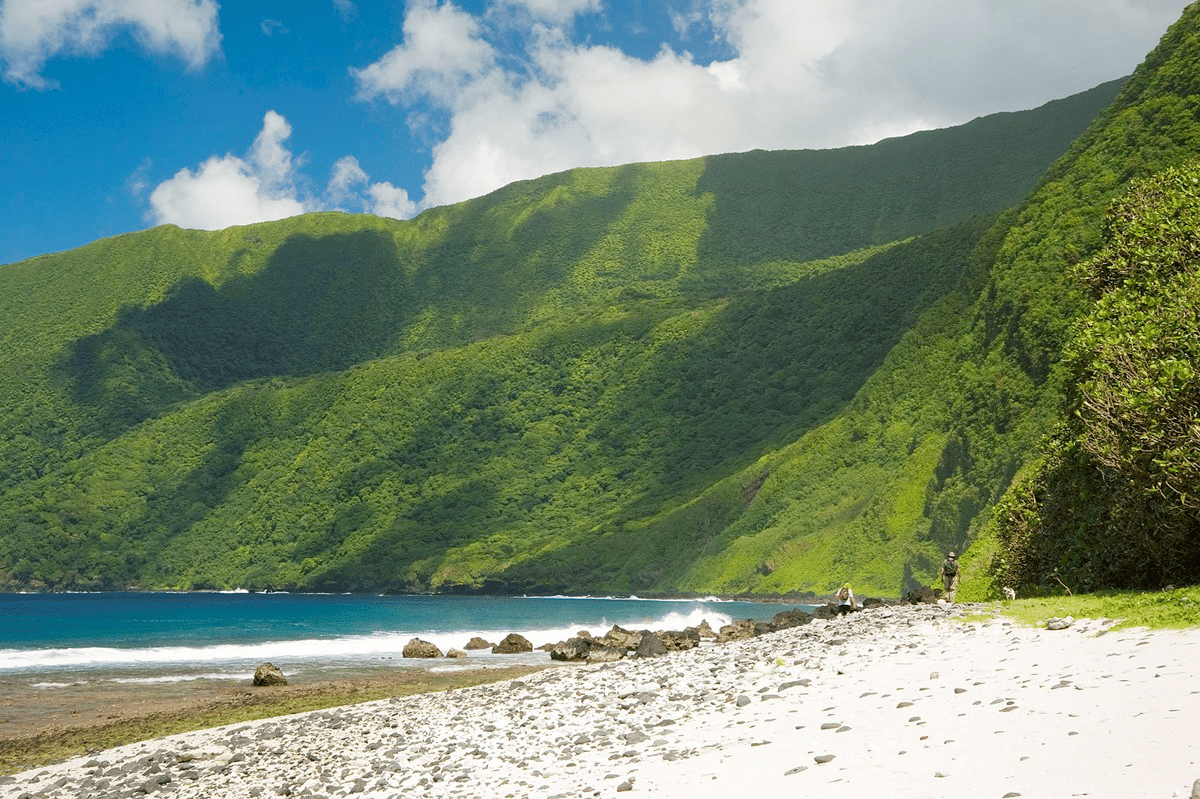 Siu Point on Ta'u Island in American Samoa, with green mountains rising above a sandy beach. 