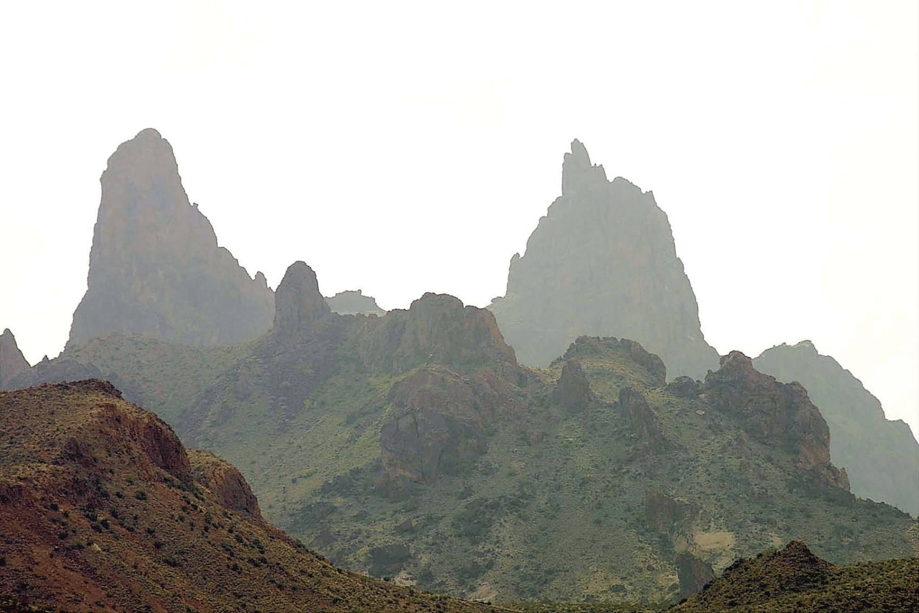 Jagged mountains in the foreground and background form the shape of Mules Ears in the distance.