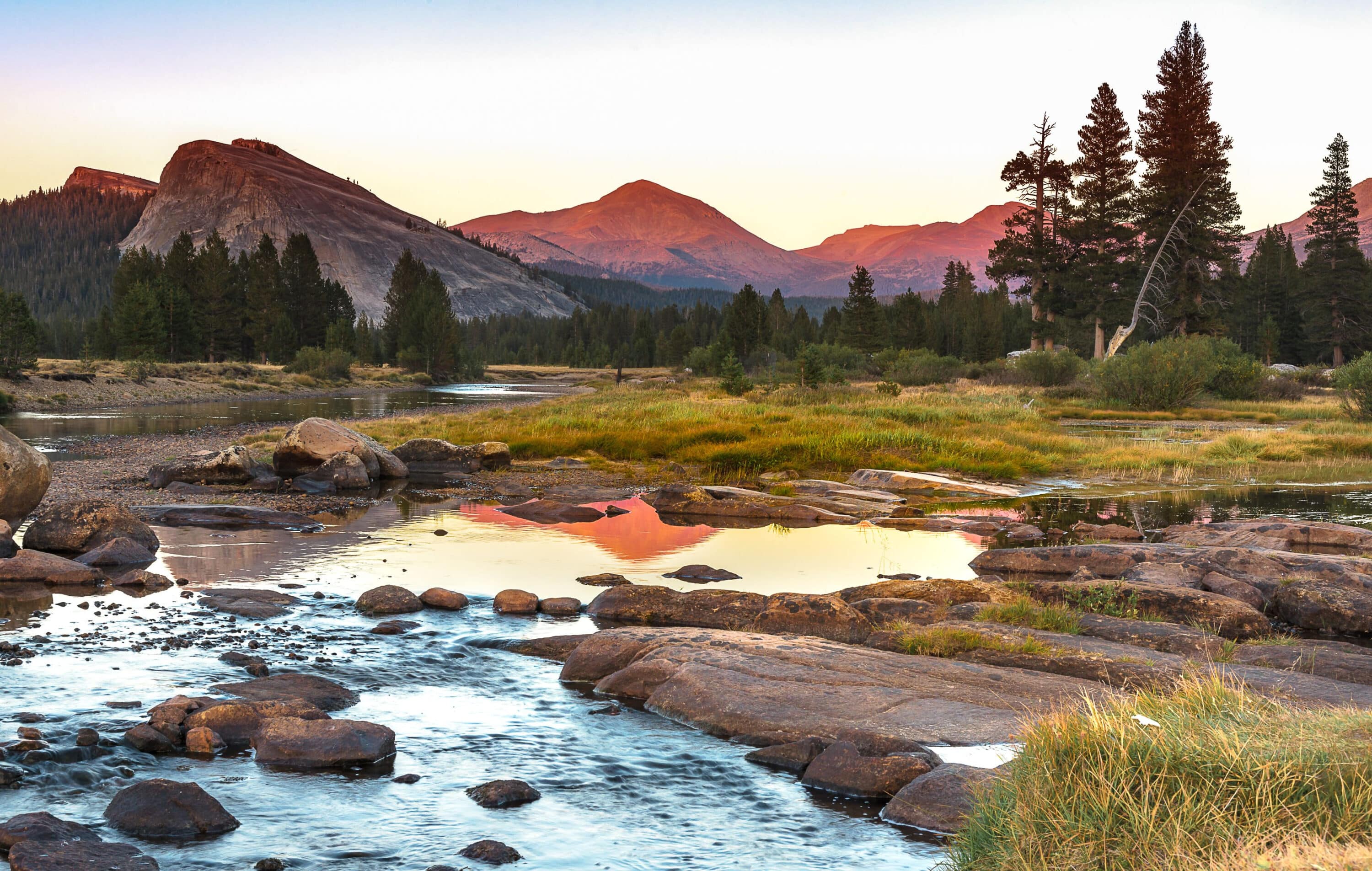 Yosemite Meadows with water in the foreground and rust-tinged mountains in the background.