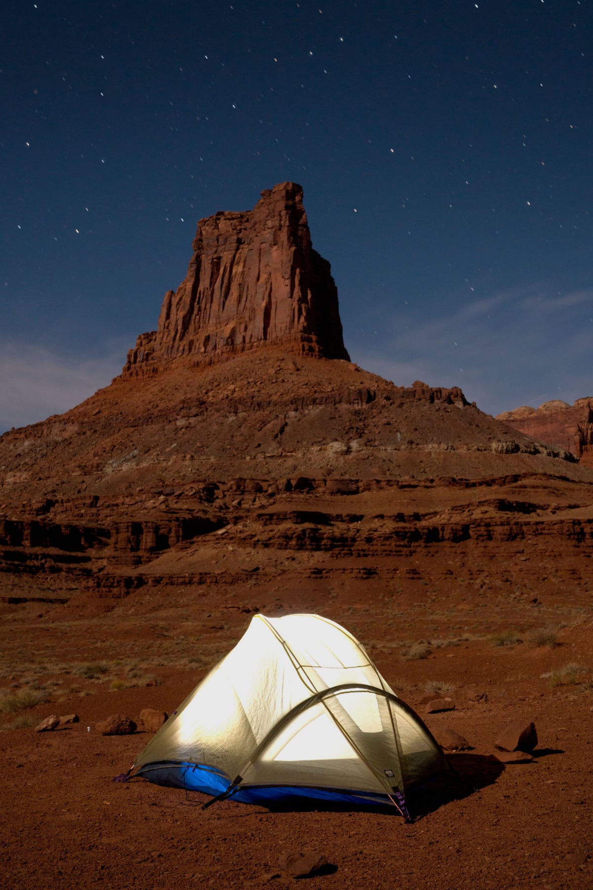 A white tent stands out among a mesa at night in Canyonlands National Park.