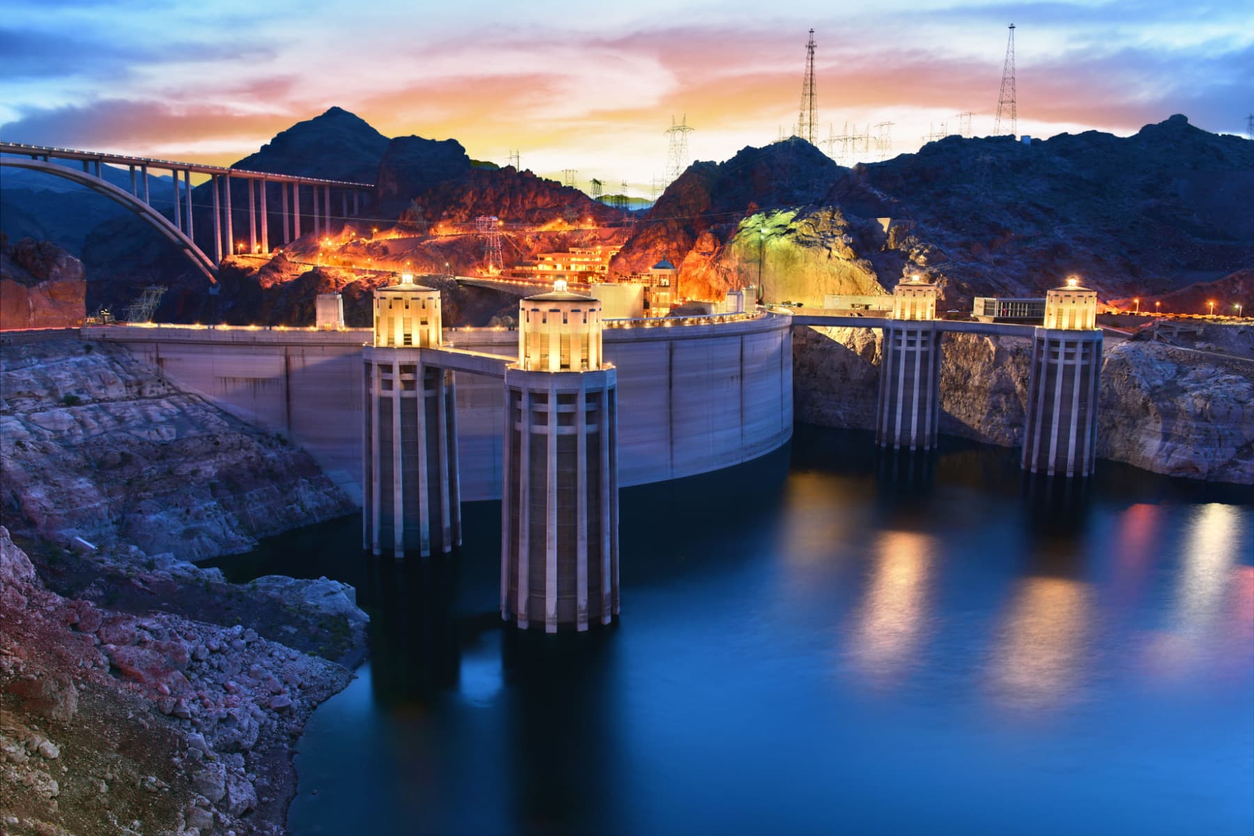 Hoover Dam with mountains as the sun sets in the background.