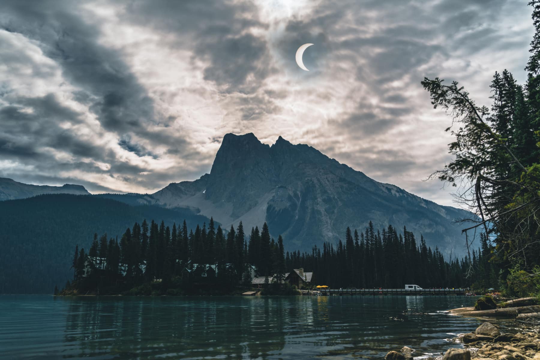 Partial eclipse hanging in the sky over mountains in Canada.