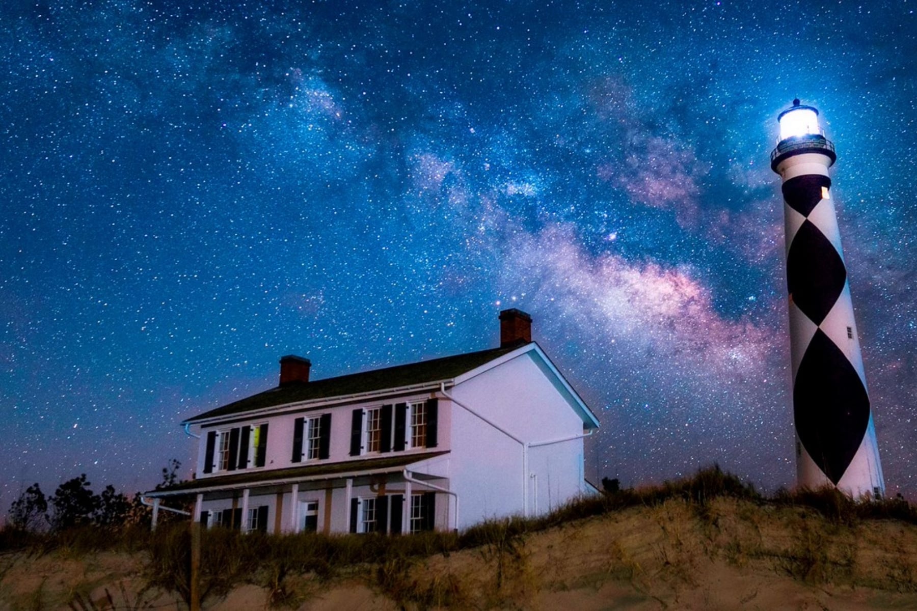 house and lighthouse with the Milky Way above.