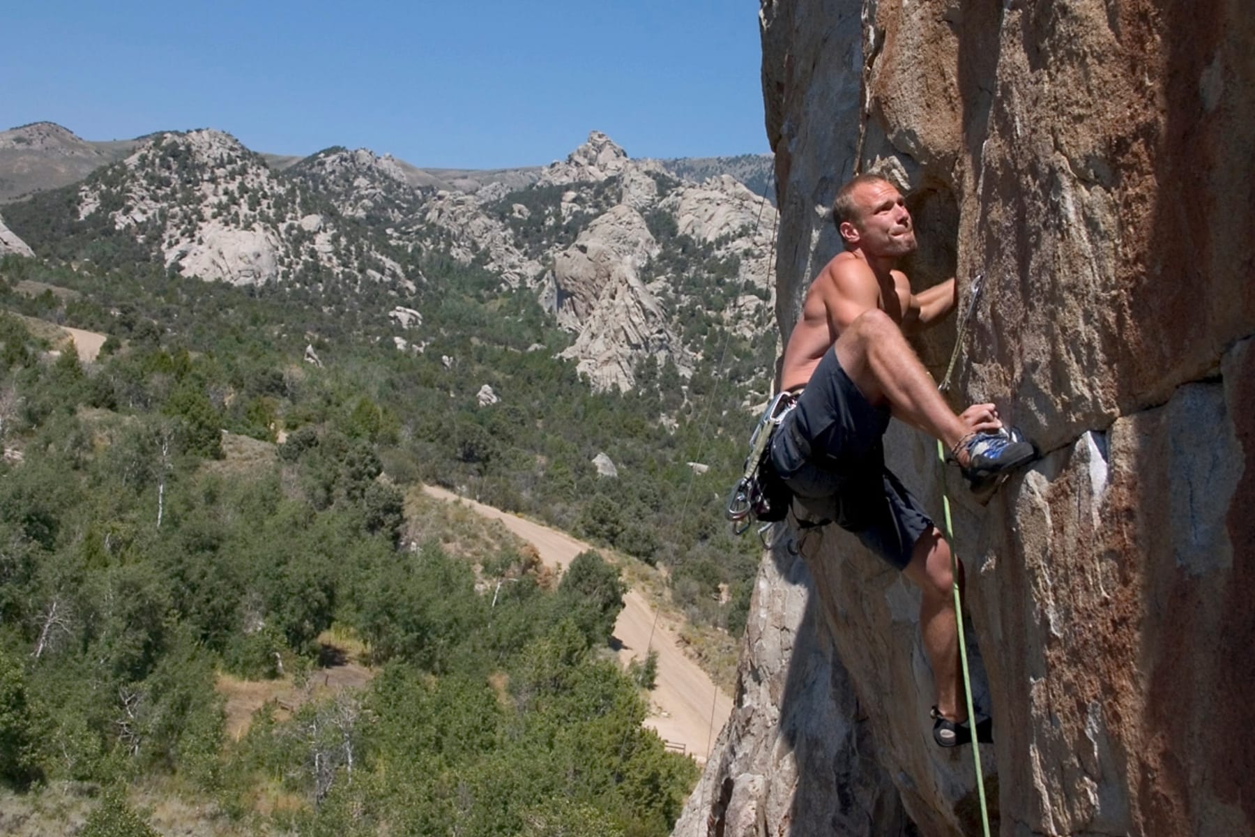 rock climber on a vertical wall with mountains in the background. 