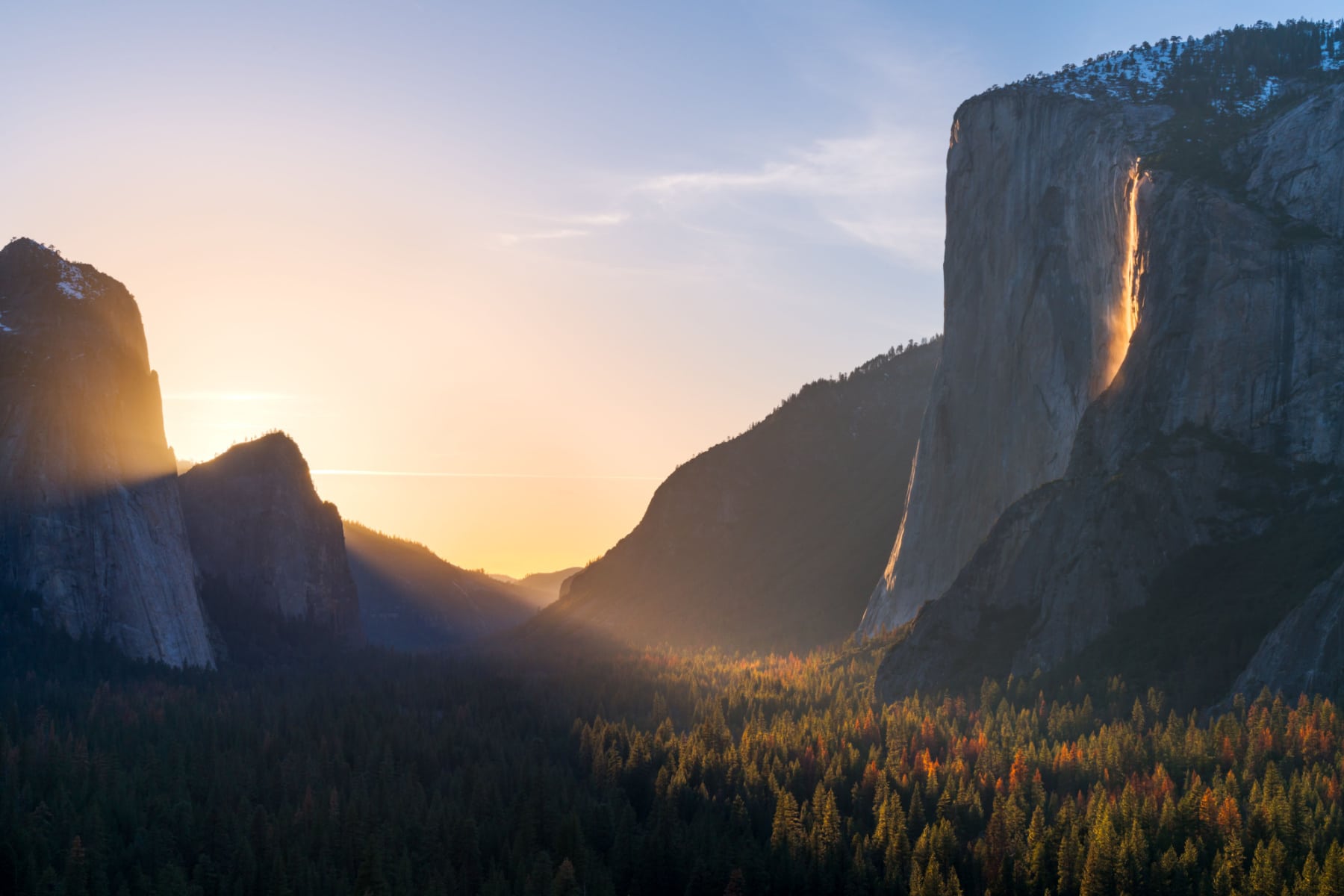 A wide shot of Yosemite Valley with the Firefall on the right side, dropping down from El Capitan.