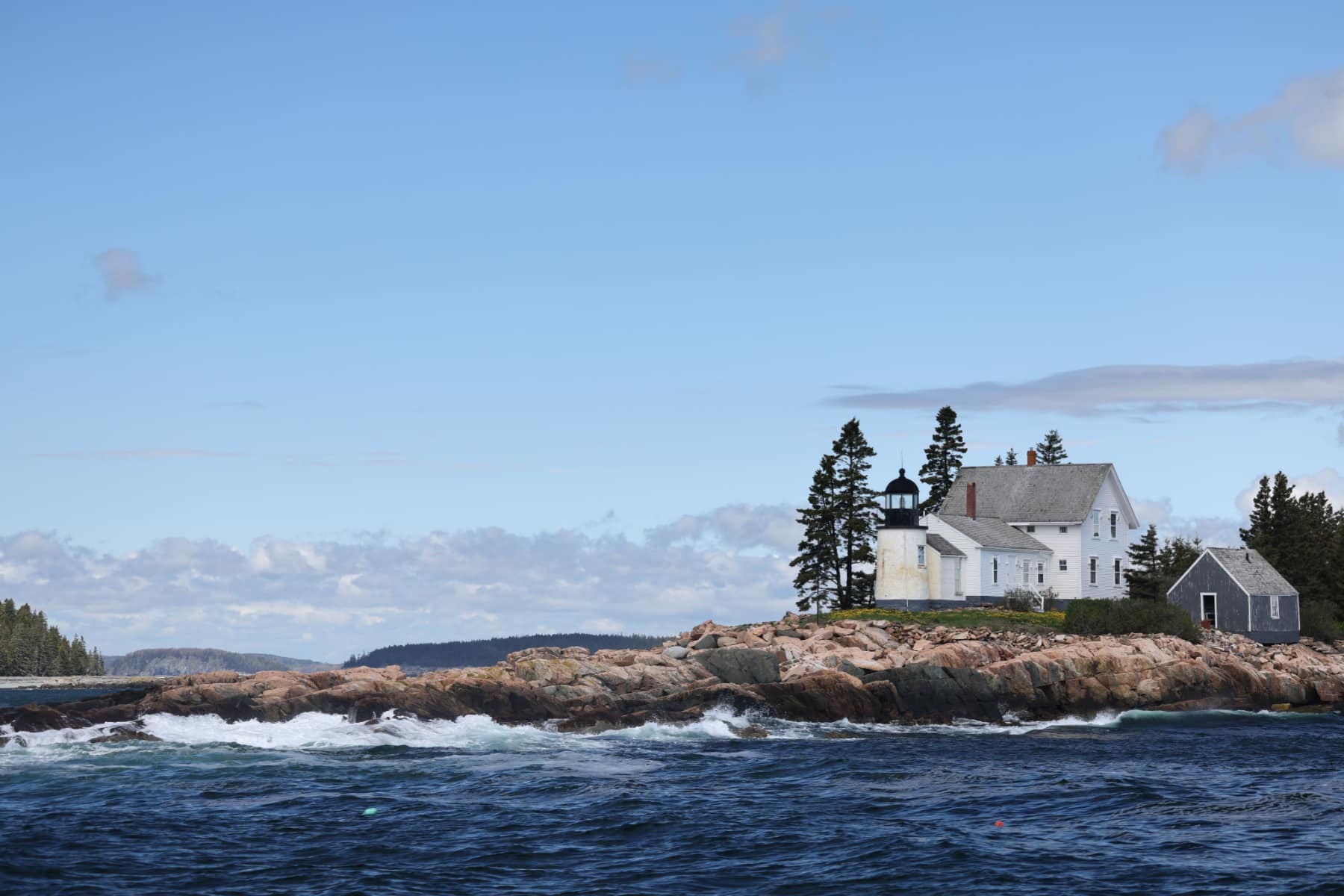 Winter Harbor Lighthouse surrounded by rocks and Frenchman's Bay in Maine.