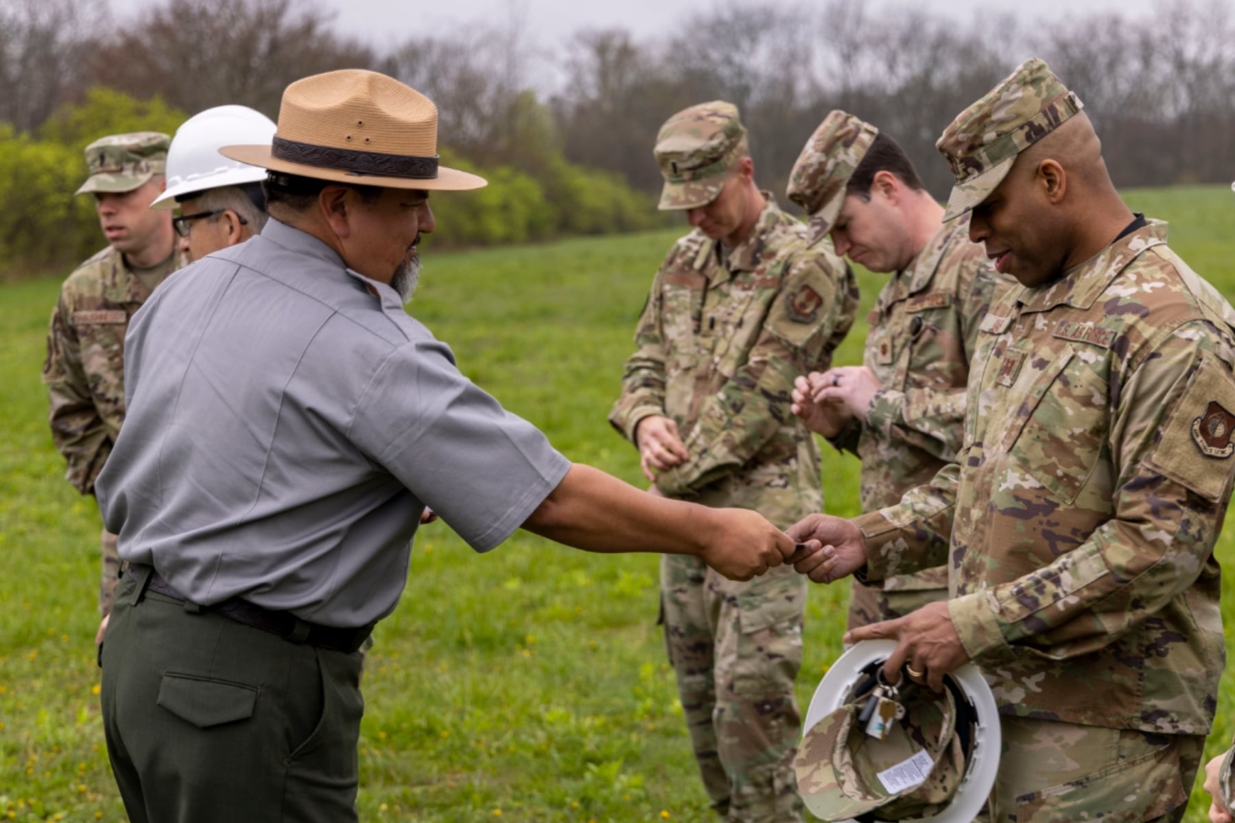 An NPS worker hands a pass to a group of military members wearing camos. 