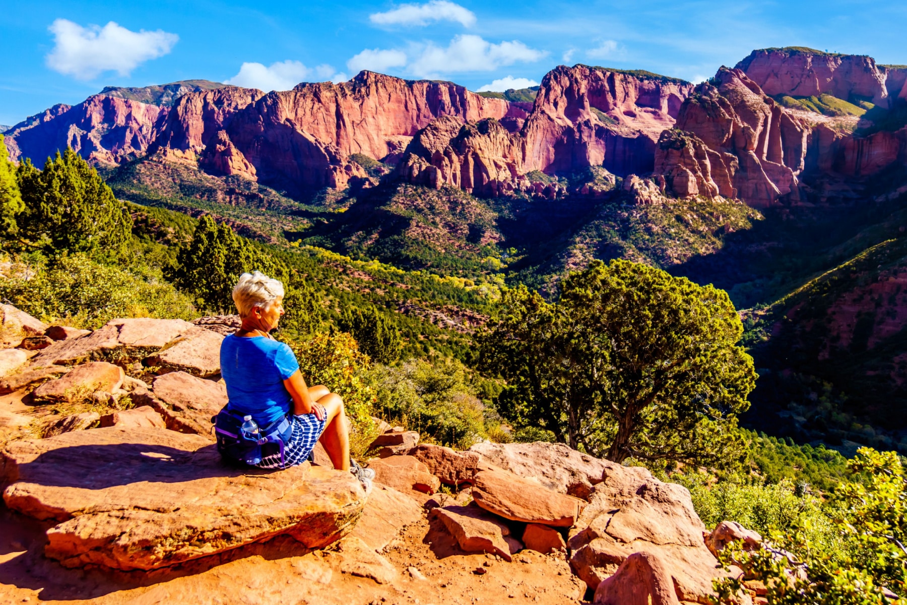 A woman sits on a rock enjoying the mountains of Zion National Park.