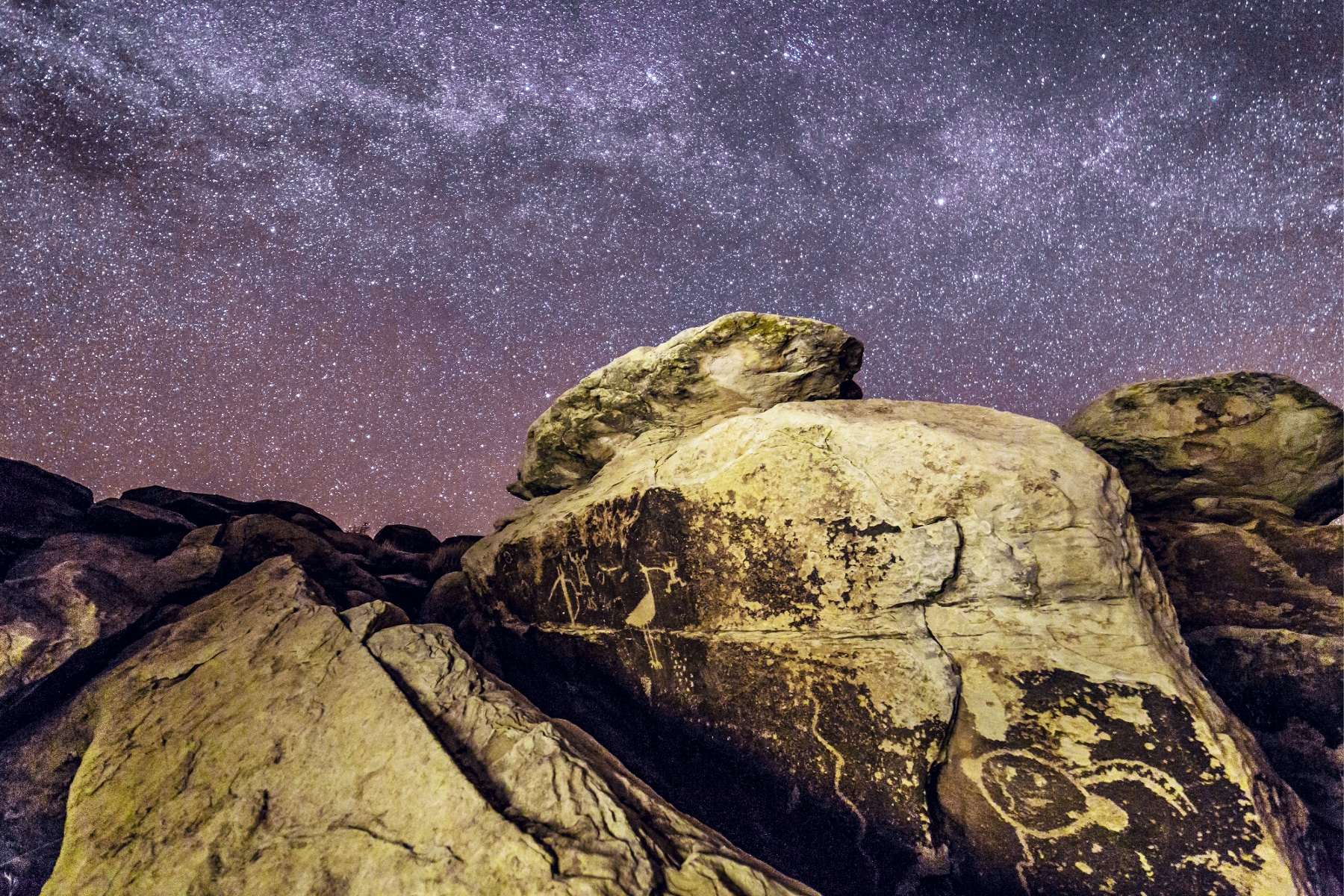 Rocks and Petroglyphs below a starry night sky at Petrified Forest National Park. 