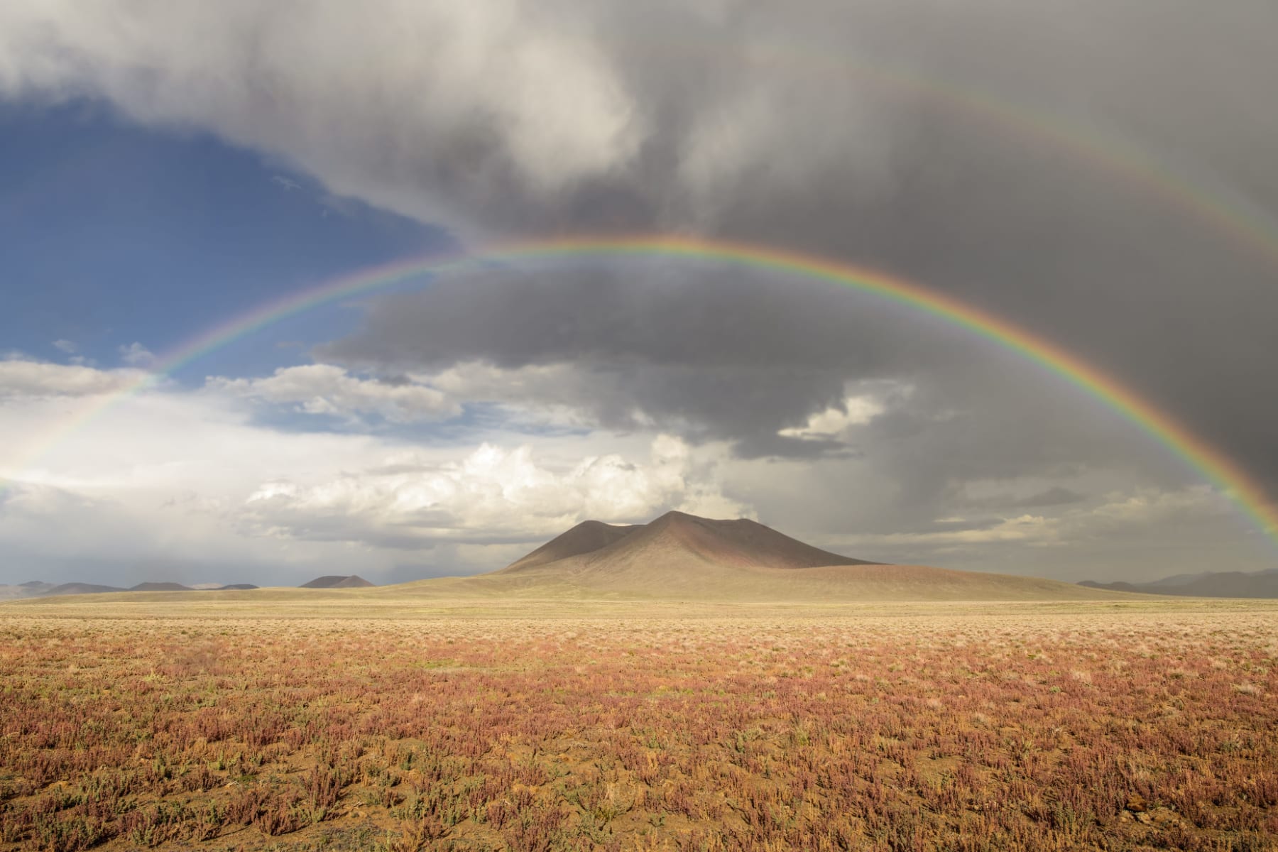 A volcanic crater with a rainbow overhead.