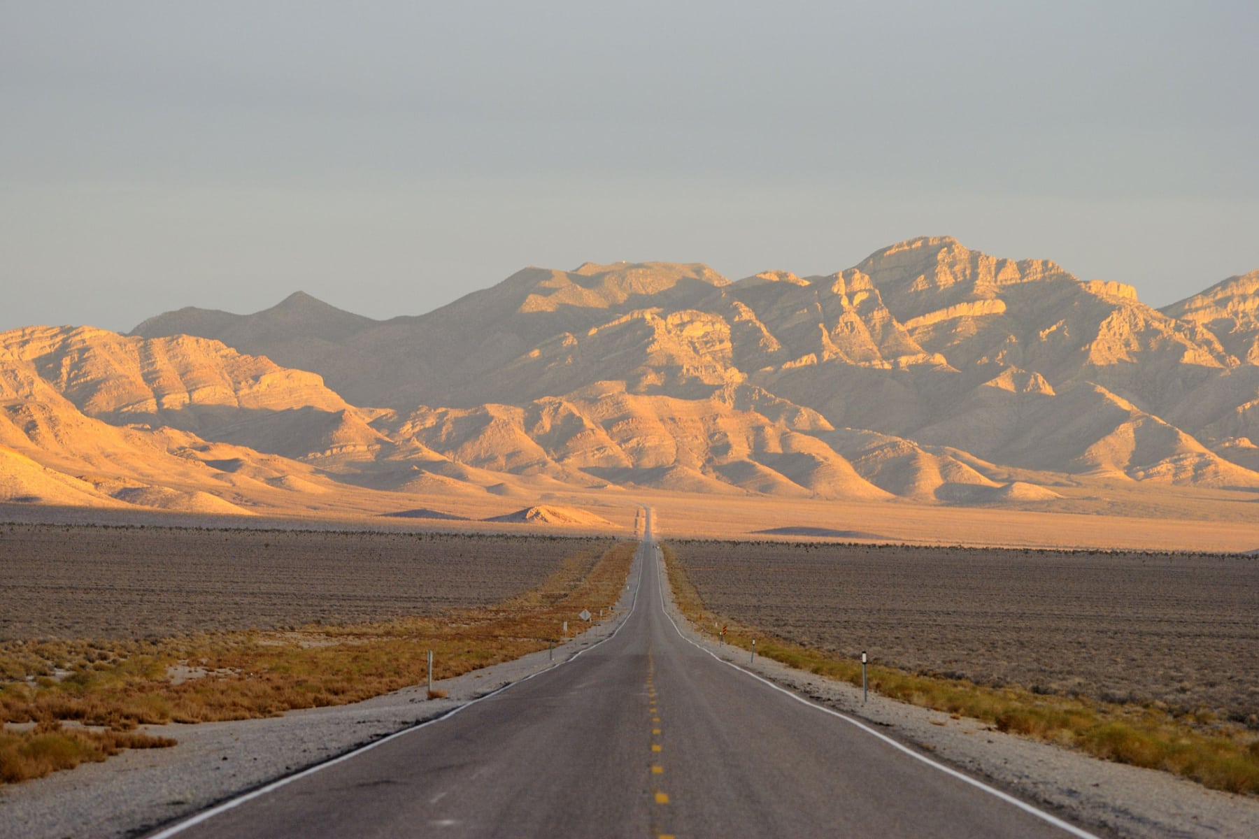 The Extra Terrestrial Highway in Nevada is a long, straight road with desert mountains ahead. 