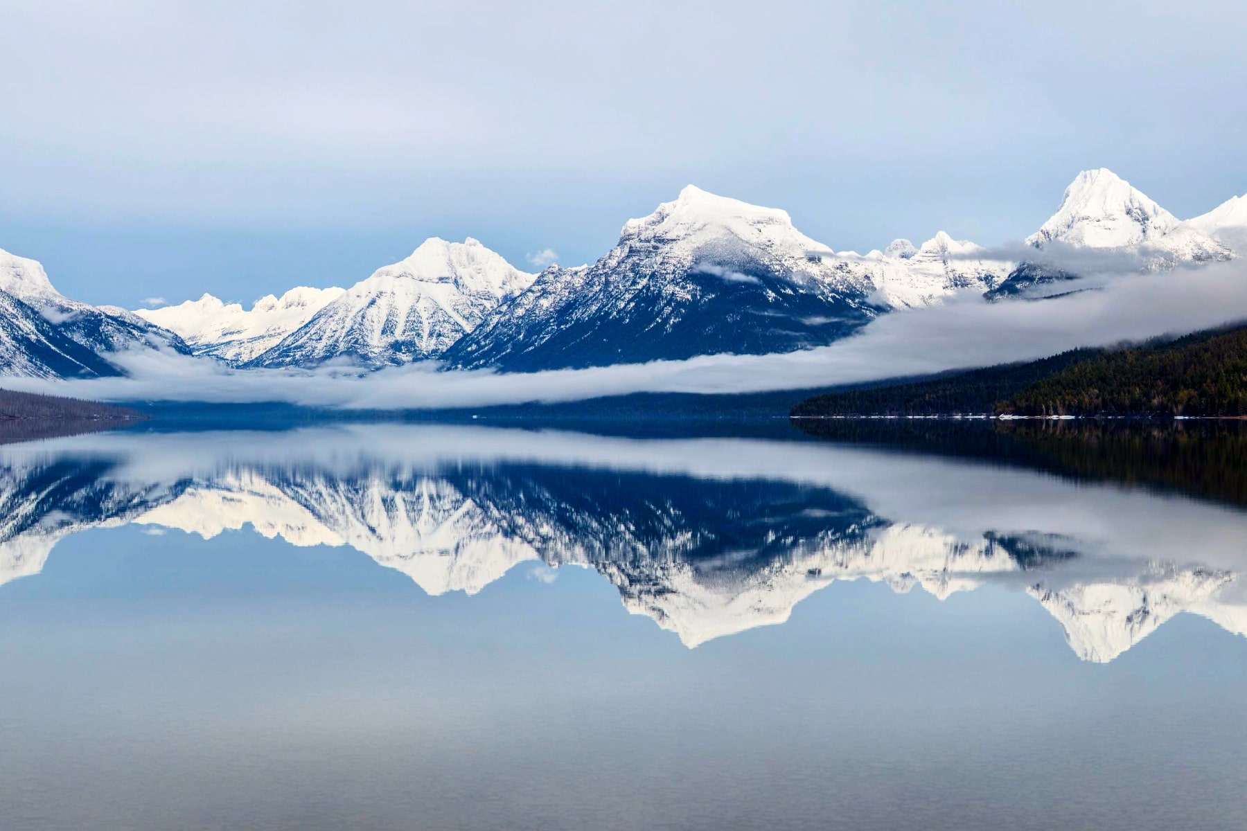 Mountains reflect on Lake McDonald, making this one of the best national parks to visit in March for those seeking winter solitude