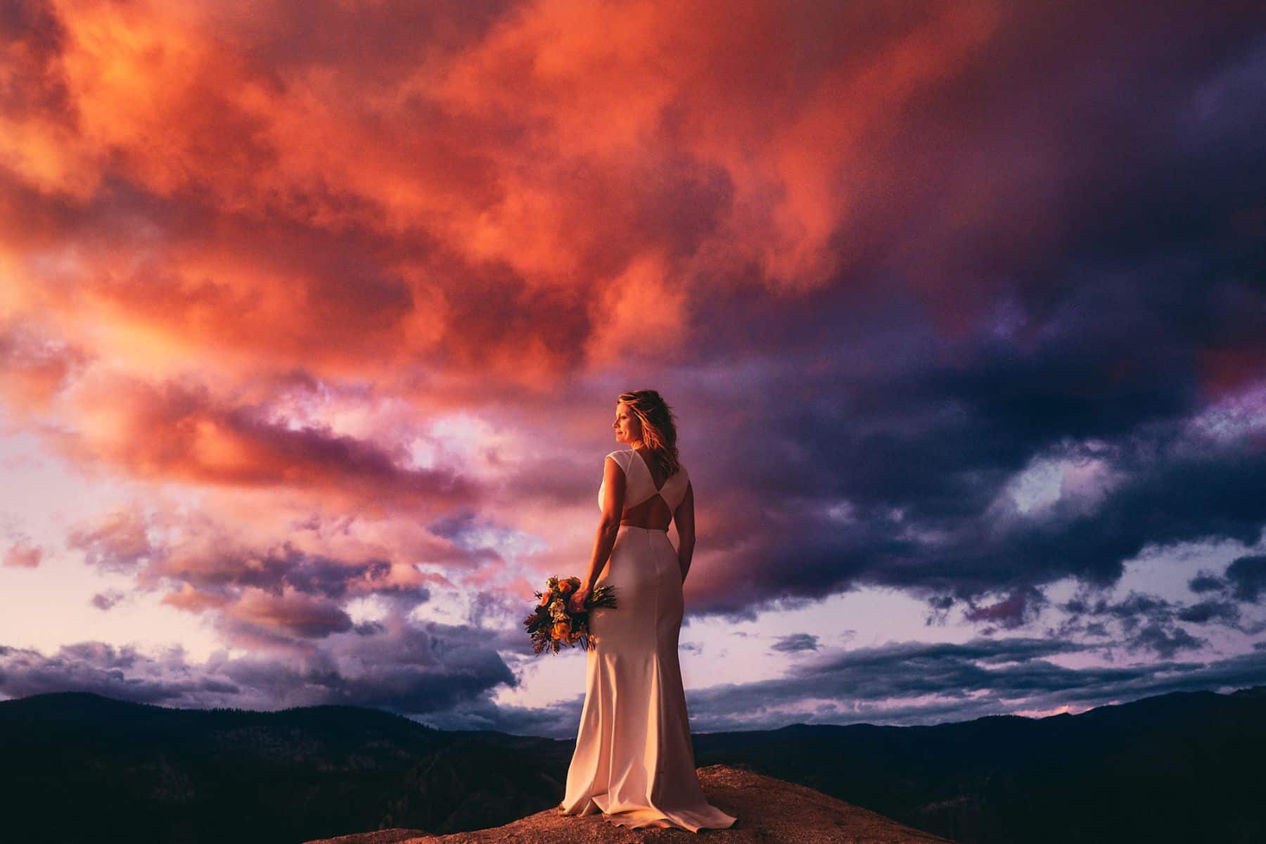 A bride stands on a ledge at Yosemite National Park after a national park wedding