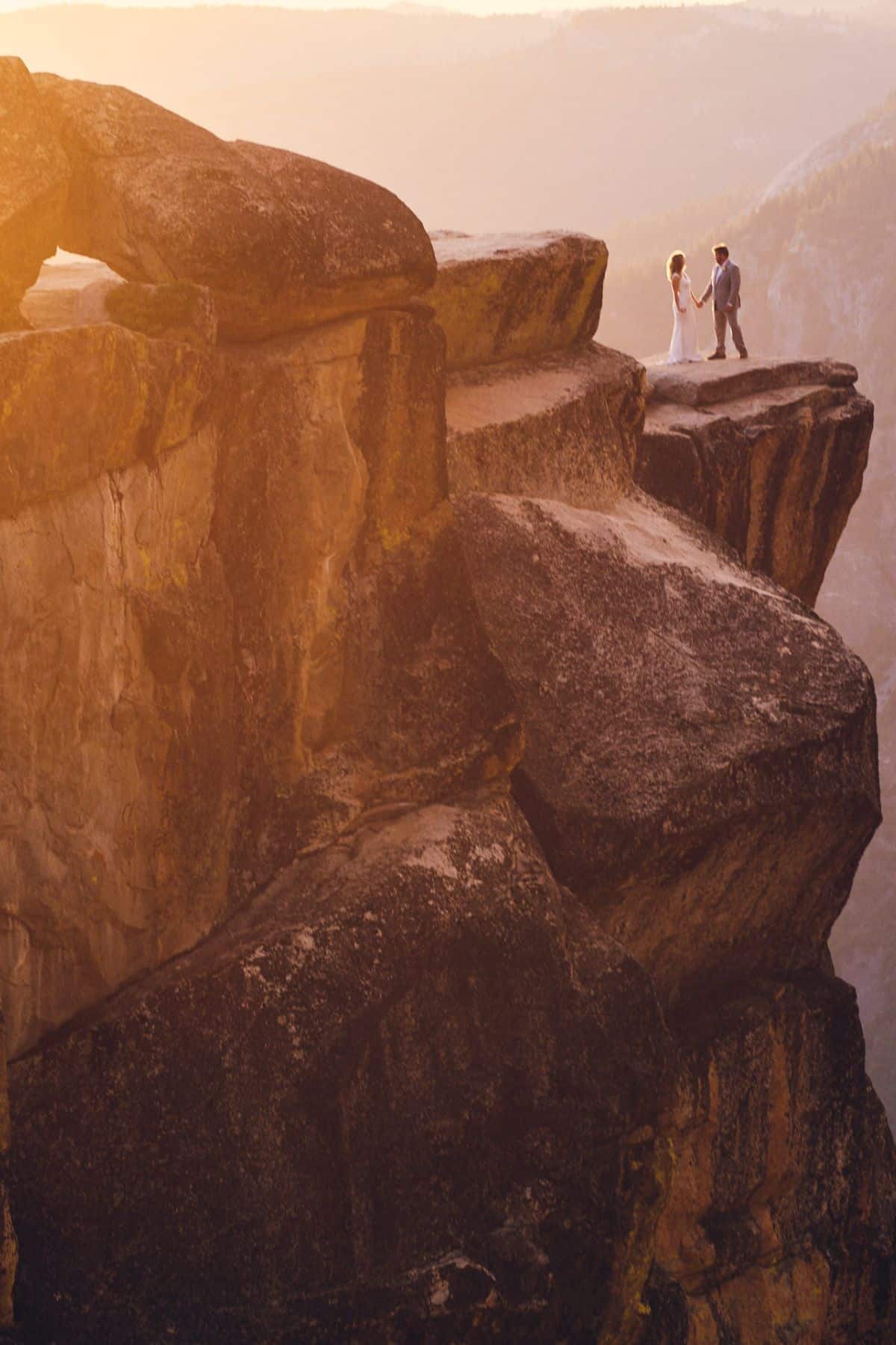 Yosemite National Park Wedding with a couple standing on he edge of a cliff in the distance
