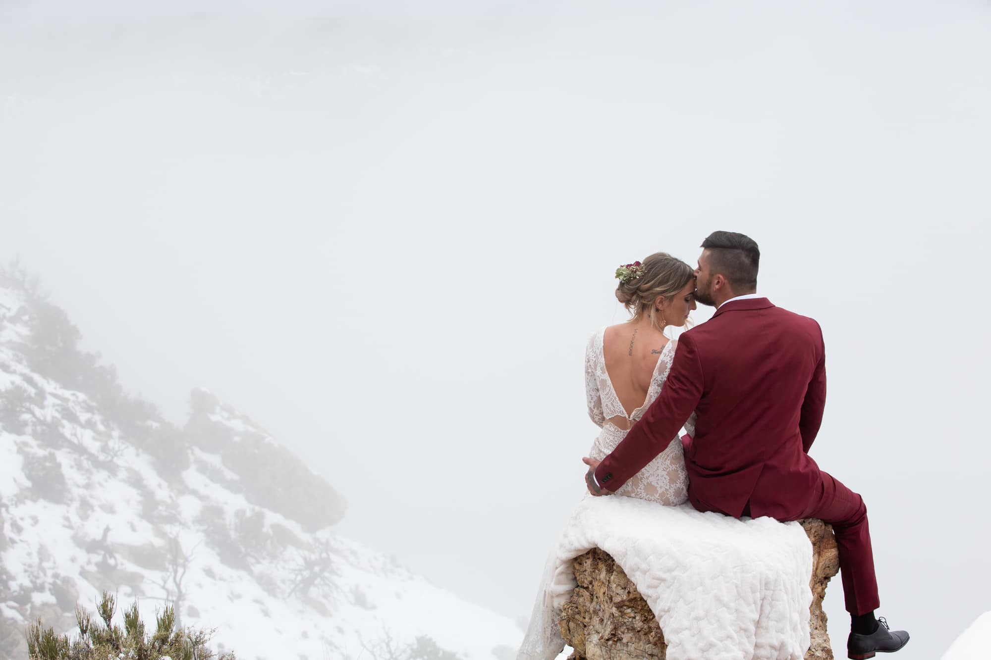 A bride and groom embrace among the snow at Grand Canyon National Park.